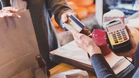 Hand of customer giving credit card to store cashier at checkout