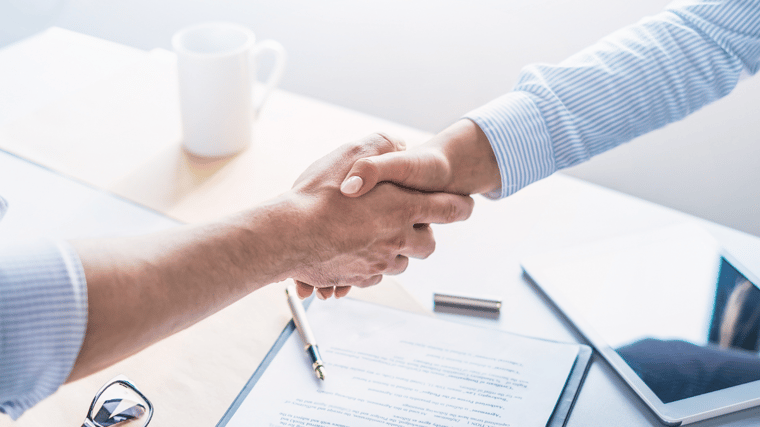 hands shaking over signed business documents