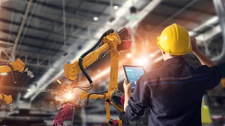 Engineer using tablet check and control automation robot arms machine in intelligent factory industrial on monitoring system software. Welding robotics and digital manufacturing operation.