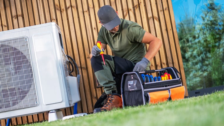 an HVAC contractor kneels down to look in his toolbox